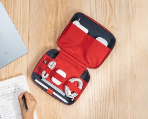 Red Marshal Tech Kit organiser from DailyObjects opened on a desk, neatly holding cables, chargers, and gadgets.