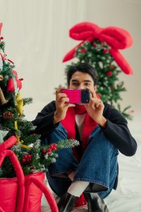 Man taking a photo with a DailyObjects Pink Parade festive phone case — bold Christmas-themed Secret Santa gift for men.