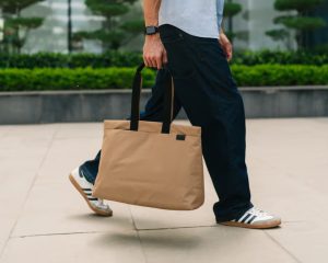 Man walking with the DailyObjects PIVOT Weekender in tan — lightweight ripstop travel bag for short trips and holiday packing.