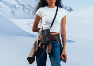 Close-up of a rider holding a Royal Enfield x DailyObjects Stride Phone Case with ‘The Stakeout’ artwork next to a motorcycle