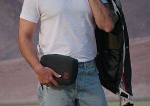 Rider holding the Royal Enfield x DailyObjects Vault Tech Organiser while standing beside a motorcycle