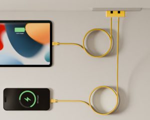Yellow multi-port charging hub powering tablet and phone with neatly routed cables on a clean wall-mounted setup.