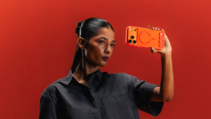 Woman holding a DailyObjects Stack Clear phone case in Flamingo tint, showing the MagSafe ring and modular dot pattern